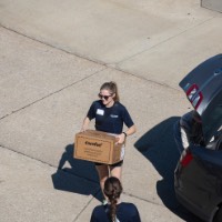 Birds Eye view of GVSU alumna unloading a cardboard box out of car